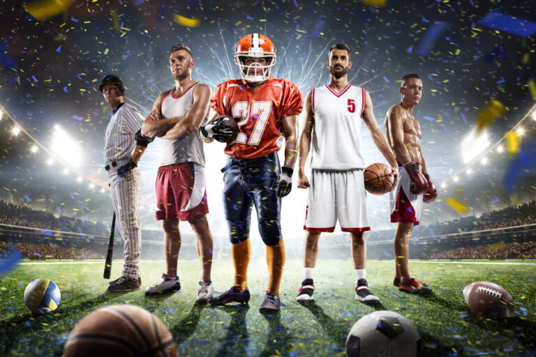 A dynamic group of five male athletes from different sports—baseball, basketball, American football, and boxing—standing confidently on a brightly lit stadium field, with various sports balls scattered in the foreground and celebratory confetti falling around them.